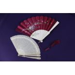 An early 20th century floral painted crimson cloth fan, 24cm and another with pierced ivory