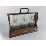 An Edwardian inlaid mahogany tantalus containing three cut glass spirit decanters, the case with