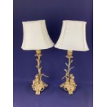 A pair of gilt metal figural table lamps each with a seated child, one holding a dove the other a