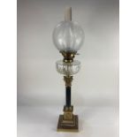 A brass Corinthian column table oil lamp with floral etched globe shade above fluted clear glass