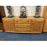 An Ercol pale wood sideboard with three central drawers, the top with fitted cutlery tray, two