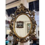 A modern Rococo style gilt framed oval wall mirror, with pierced scroll frame, frame 97cm by 70cm