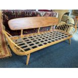 An Ercol pale wood studio couch with bar back and spindle side supports, webbed base on splayed