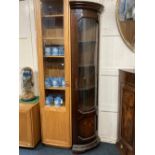 A reproduction glazed mahogany corner cabinet with tall bow fronted glass panelled door enclosing