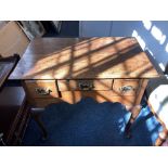 A 19th century oak lowboy with rectangular top three drawers with brass drop handles, shaped