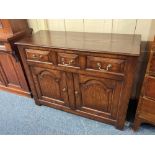 A George III style small oak sideboard, with three drawers and two arch panelled cupboards 107cm