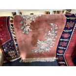 A Chinese rug, orange pink ground, with floral decoration, 180cm by 76cm