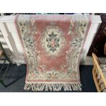 A Chinese wool rug, the central floral motif within pink ground, and floral line border, 90cm by