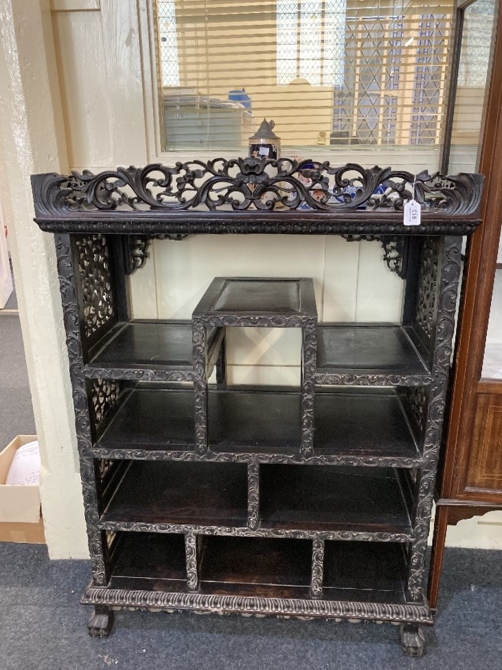 A Chinese carved hardwood display cabinet with pierced scroll gallery surmount above an