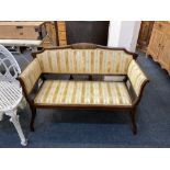 An Edwardian inlaid mahogany small settee, the gently arched back with central panel of musical