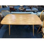 An Ercol pale wood dining table with rounded rectangular top on splayed tapered legs, catalogue