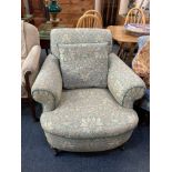 A Howard & Sons style club chair, with William Morris type upholstery, on turned legs and castors