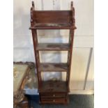 A narrow mahogany bookcase with four open shelves and two small lower drawers and pieced side