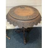 A profusely carved Eastern circular side table with shaped overhanging top decorated with animals