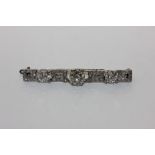 A diamond bar brooch claw set with three principal round stones with pavé set Greek key motifs