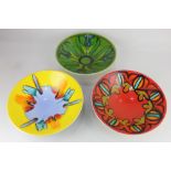 Three Poole pottery bowls, each decorated with patterns in bright colours, 27cm diameter