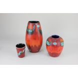 Two Poole pottery vases, with abstract decoration in blue, green, orange and black on red ground,