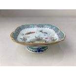 A small Chinese porcelain dish, with lobed rim, raised on a circular foot, decorated with