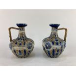 A near pair of Doulton Lambeth pottery oil jugs one by Elizabeth Atkins the other ET, with raised