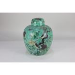 A porcelain ginger jar and cover, decorated with birds amongst flowering branches, on green