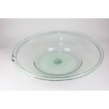 A green glass milk or cream dish, circular form with spout, rough pontil mark to base, 60cm