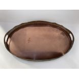 A large oval copper serving tray, with scalloped and pierced gallery, and two handles, 61cm wide
