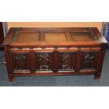 An oak coffer with gothic style carved panel front and metal strap hinges 113cm
