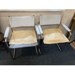 A pair of modern chromed frame chairs with white leather back straps, seats and arm pads, on