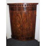 An early 19th century banded mahogany bowfront hanging corner cabinet two cupboard doors with