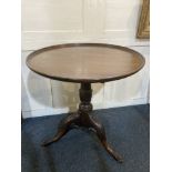 A 19th century mahogany circular tea table, with tilt top on carved baluster stem and tripod base