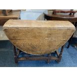 An 18th century oak gateleg table with oval top on turned supports and low stretchers, opens to