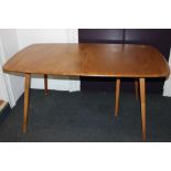 An Ercol pale wood extending dining table, with rounded rectangular top, on slanted tapering legs