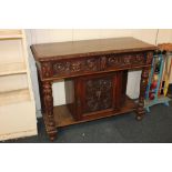 A Victorian carved oak side table, the rectangular top above two drawers carved with mask handles