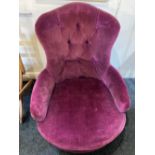 A Victorian button upholstered low chair in purple fabric on baluster legs with brass ball castors