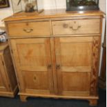 A pine cabinet, with two drawers and cupboard enclosing shelves on bracket feet 107cm