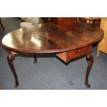 An 18th century drop leaf dining table, with oval top, on four scroll carved cabriole legs with hoof