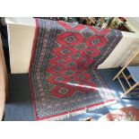 A Pakistani wool rug the central geometric pattern within multi-line borders on red ground (a/f -