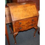 A Queen Anne style walnut bureau with fitted interior of small shelves and pigeon holes, two drawers