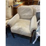 An Edwardian upholstered armchair with carved harebell framed arms on fluted column legs and spade