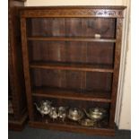 An oak open bookcase with three adjustable shelves and carved lunette and scroll decoration, on