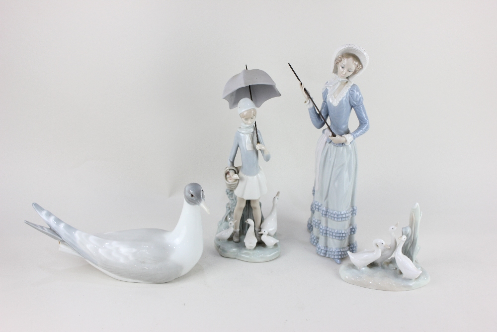 Two Lladro porcelain figures of ladies carrying umbrellas (one missing its canopy), to include a