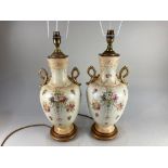 A pair of Victorian baluster vases now as table lamps, decorated with floral sprays on cream
