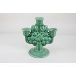 A Poole pottery three branch candelabra, green ground, decorated with fruiting vines, on octagonal