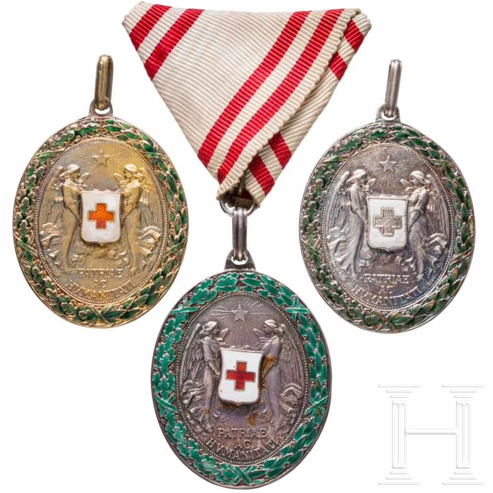 Three Red-Cross medalsDrei Ehrenmedaillen in Silber mit Kriegsdekoration. Eine am Dreiecksband, eine