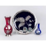 Zwei Vasen und eine runde Platte, 20. Jh., verschiedene Hersteller, jeweils mit farbigem