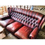 AN OXBLOOD LEATHER BUTTON BACK THREE SEATER SOFA