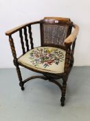 AN OAK BOW CHAIR WITH FLORAL NEEDLE CRAFT UPHOLSTERED SEAT AND RATTAN PANEL TO BACK