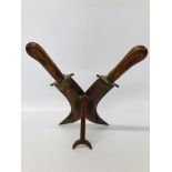 DECORATIVE DOUBLE KNIFE ON CARVED WOODEN DISPLAY STAND WITH BRASS DETAIL,