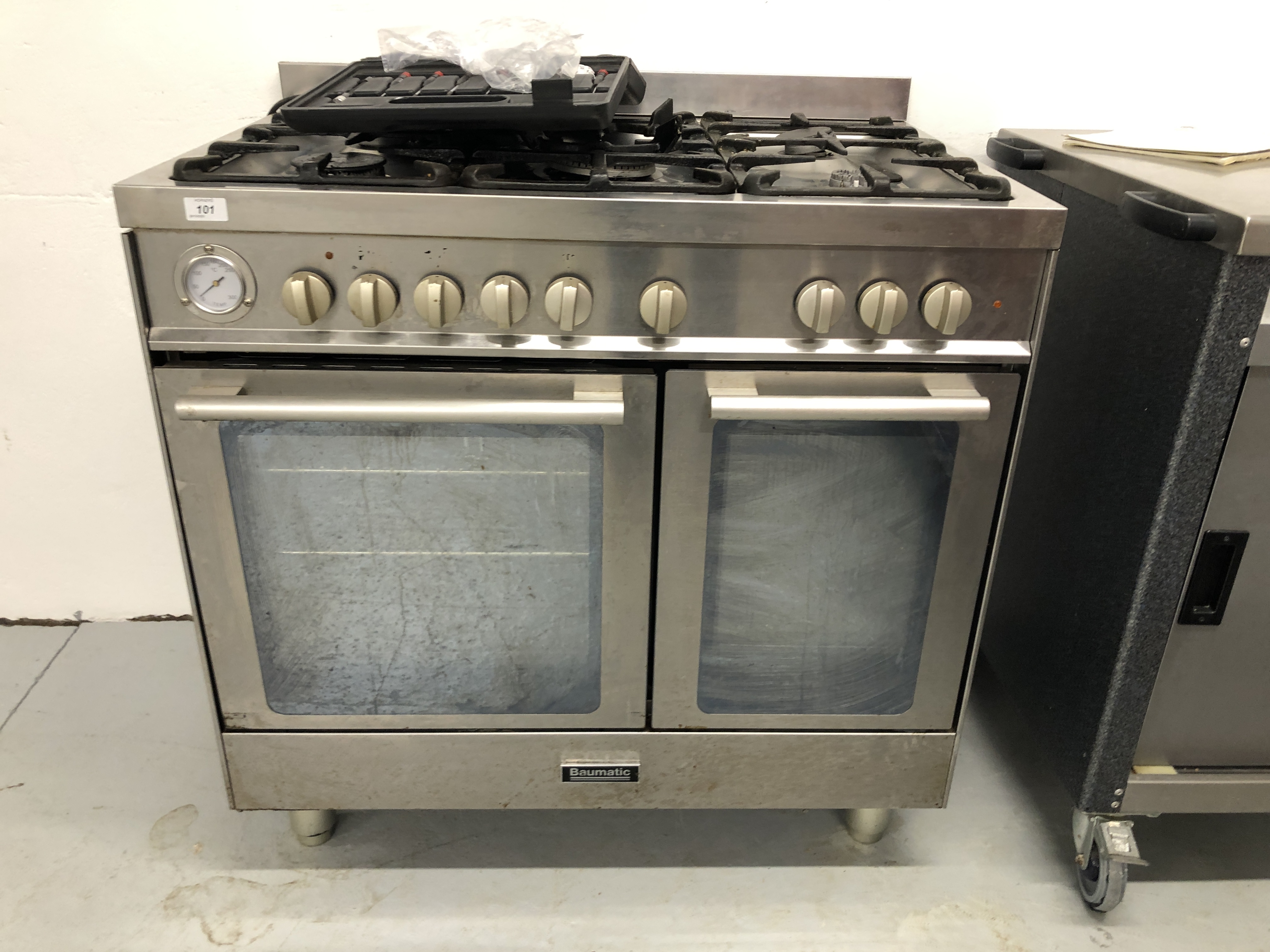 A BAUMATIC STAINLESS STEEL MAINS GAS DOMESTIC COOKING RANGE (REAR LEG BROKEN) - TRADE ONLY - SOLD
