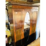 AN EDWARDIAN MAHOGANY WARDROBE WITH OVAL MIRRORED DOOR AND BLANKET DRAWER TO BASE